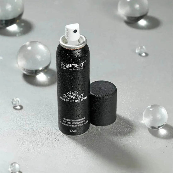 24 Hrs Smudge-Free Makeup Setting Spray bottle on a reflective surface with droplets, emphasizing long-lasting, hydrating formula.