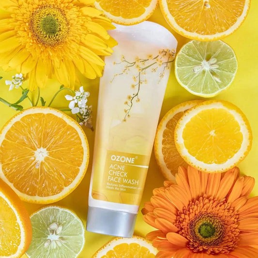 Acne Check Face Wash 100g tube surrounded by citrus fruits and flowers, promoting clear and oil-free skin.