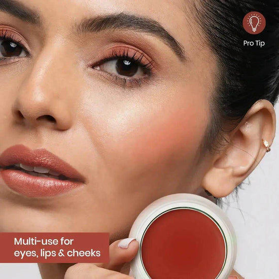 Person applying multi-use makeup for eyes, lips, and cheeks, showcasing a warm, natural glow with a rich caramel shade.